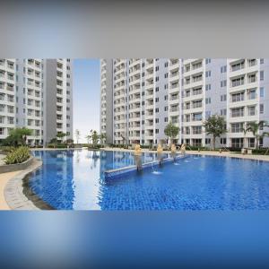 スラバヤにあるPAKUWON MALL Apartemen Orchard Anderson Tanglin Bensonの高層ビルの前の大きなプール