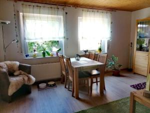 a living room with a table and chairs and two windows at Ferienwohnung Maifeld in Wierschem