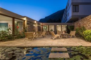 a patio with chairs and a pond in front of a building at Amalia Hotel Delphi in Delphi
