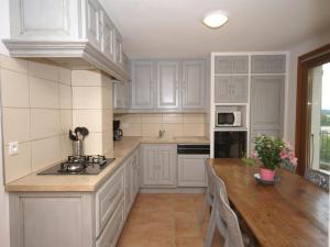 a kitchen with white cabinets and a wooden table at Captivating Holiday Home in Les Vans with Pool in Les Vans