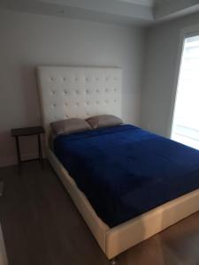 バンクーバーにあるmetropolitan 2-Bedroom condo Oak stの青い毛布が掛けられた大きなベッドのある寝室