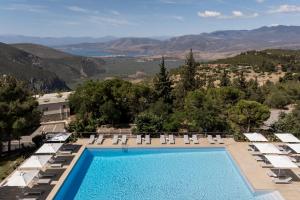 a pool with chairs and a view of the mountains at Amalia Hotel Delphi in Delphi