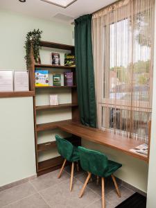 een kamer met een bureau en 2 groene stoelen bij Balance Apartman Debrecen in Debrecen