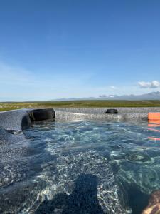 a swimming pool filled with water next to a beach at Lindarhóll Guesthouse in Stóri-Bakki