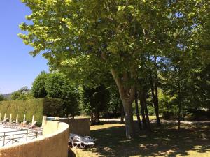 a group of chairs and a tree in a park at A beautiful 2 persons studio in a chateau with swimming pool in Montbrun-les-Bains