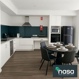 een keuken met een tafel, stoelen en apparatuur bij Spacious Accessible with Bathrooms for Everyone in Alkimos