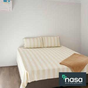 een bed met een gestreept dekbed in een kamer bij Spacious Accessible with Bathrooms for Everyone in Alkimos +3 foto's