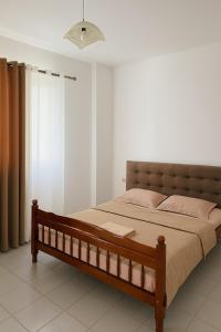 a bedroom with a wooden bed with pink pillows at Hotel Ardian in Golem +4 photos