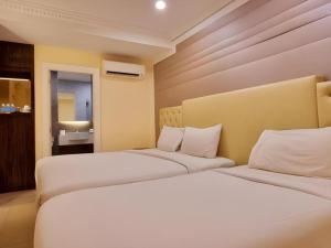 Dos camas blancas en una habitación con baño. en Ritzton Hotel, en Johor Bahru
