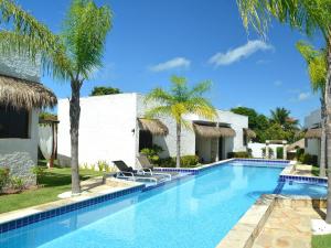 - une piscine avec 2 chaises longues à côté d'une maison dans l'établissement Oasis Tajaja Pousada, à Jacumã