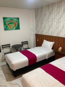 a bedroom with two beds and a table at Hotel Sanrina Kuta Bali in Kuta +30 photos