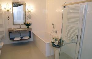ein weißes Bad mit einer Dusche und einem Waschbecken in der Unterkunft Schloss Hotel Wolfsbrunnen in Schwebda