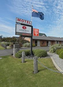una señal de motel con una bandera frente a un edificio en Admiral Court Motel & Apartments, en Invercargill
