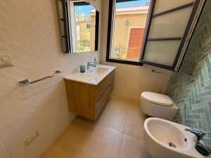 Un baño con lavabo, inodoro y espejo. en HoneyMoon Suite Apartment, en SantʼAlessio Siculo