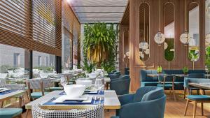 ein Esszimmer mit Tischen und Stühlen und Fenstern in der Unterkunft Mövenpick Hotel & Residences Teuta Kotor Bay in Kotor