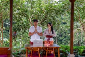 a man and a woman doing yoga in front of a laptop at Yama Villa & SPA Ubud in Payangan
