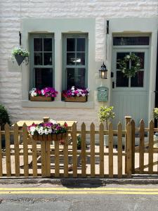una staccionata di legno con fiori alle finestre di una casa di Historic 1600’s The Grocer’s Cottage a Heysham