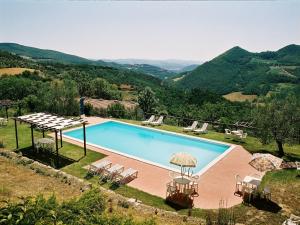 a pool with chairs and umbrellas next to a mountain at Farmhouse with stables, horses and the ability to make horseback riding in Monte Santa Maria Tiberina +100 photos