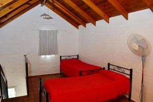 two red beds in a room with a fan at Complejo Las Hoyas in Villa Carlos Paz +35 photos