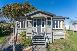 ein weißes kleines Haus mit einer Leiter, die zur Tür führt in der Unterkunft Ruapehu Cottage - Ohakune Holiday Home in Ohakune
