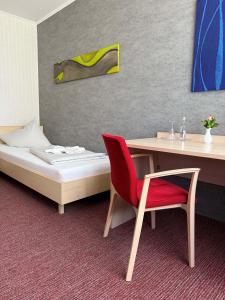 a room with a bed and a desk and a red chair at Hotel Union Salzwedel in Salzwedel