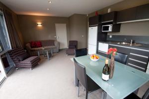 cocina y sala de estar con mesa y sillas en Bay Breeze Accommodation en Cooks Beach