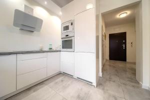 cocina con armarios blancos y TV en la pared en Kościańska Cosy Apartment, en Wroclaw