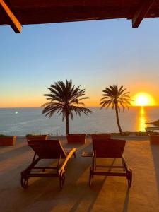 two chairs on the beach with the sunset in the background at Villa san Gaetano in Scauri