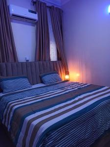 a bedroom with a large bed with a striped blanket at Abimbola's - 3 Bedroom Apartment in Lagos +6 photos
