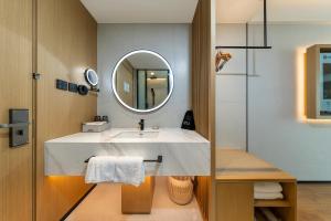a bathroom with a sink and a mirror at Floral Hotel Banlan Cangzhou Convention and Exhibition Center High-speed Railway West Station in Zhifangtou