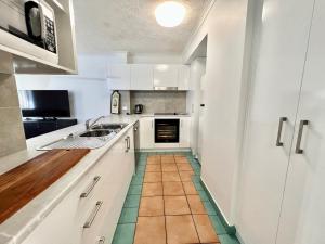 Una cocina con gabinetes blancos y azulejos verdes en el piso. en 50 K Resort Surfers Paradise, en Gold Coast
