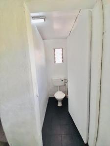a small bathroom with a toilet and a window at Private Double Room - Airport Cottage in Fua‘amotu