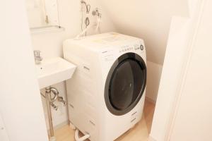 a washing machine in a bathroom next to a sink at Dori Dori House Ebisu in Tokyo