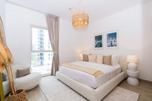 a white bedroom with a bed and a chair at One Bedroom Apartment by Otolo Homes with Free Yas Theme Park Tickets in Abu Dhabi +27 photos