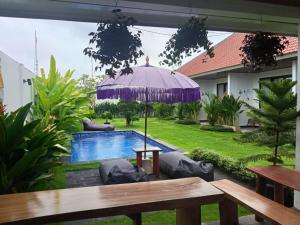 - une terrasse avec une table et un parasol à côté de la piscine dans l'établissement Kayla Homestay, à Nusa Dua