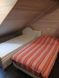 a bed with a striped comforter in a attic at Chez MU & CRIS in Mende