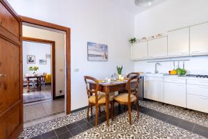 Una cocina con gabinetes blancos y una mesa y sillas. en GuestHost - Cozy Country Apartment, en Vicopisano