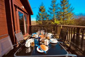 a table with food and drinks on a balcony at Luxury Woodland Lodge near Clovelly & Bude in Woolfardisworthy