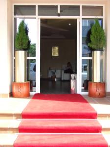 un tapis rouge devant une porte avec deux plantes en pot dans l'établissement Hotel Senator, à Slatina