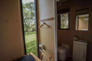 baño con aseo y puerta con ventana en Makowata Farm by Tiny Away, en Colosseum