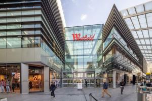 a large glass building with people walking in front of it at London Home with Garden and Parking near Stratford Station in London