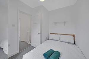a white bedroom with a bed with two pillows on it at London Home with Garden and Parking near Stratford Station in London