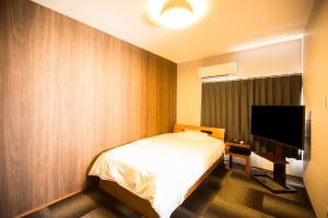 a bedroom with a bed and a flat screen tv at ファーストアベニューハウス 駅近 1組限定貸切 in Anan