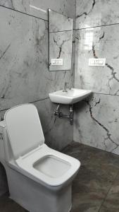 バンガロールにあるMAYURA GUEST Innの白いトイレと洗面台のあるバスルーム