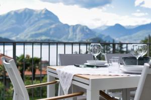 a table with wine glasses on a balcony with mountains at Hidden Gem - Villa with private swimmingpool Bellagio view in Lierna +49 photos
