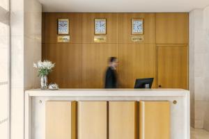 a man is standing behind a desk in a lobby at Divani Palace Larissa in Larisa