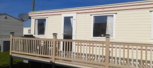 a house with a wooden railing on a deck at Static caravan in Chapel Saint Leonards +2 photos