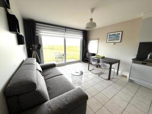 a living room with a couch and a table and a kitchen at Les Côtes - Studio Dunes Du Golf - Vue mer - WMX in Wimereux