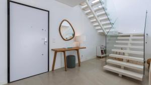 einen Flur mit einem Tisch, einem Spiegel und einer Treppe in der Unterkunft Villa Aroeira with Pool by LovelyStay in Aroeira