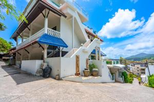a white house with a blue awning at Hotel Kata Hill Sea View in Kata Beach